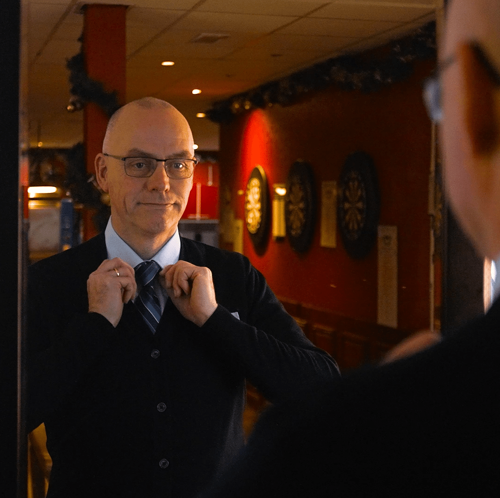 Chauffeur Paul kijkt in de spiegel en doet zijn Pouw Vervoer das goed.